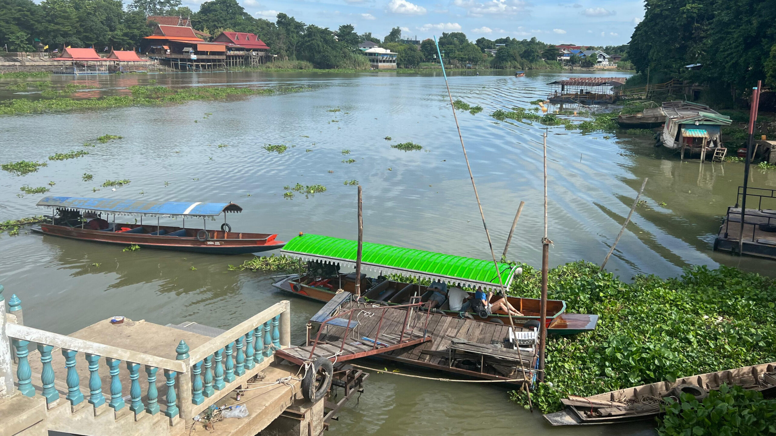 Tradional Thai boat with a tour that includes stops at three riverside temples